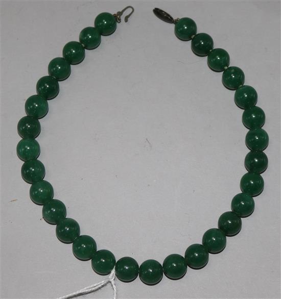 A necklace of thirty polished green jade beads, 14.25in.